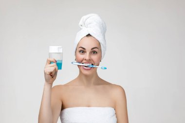 Happy young woman in towel brush her teeth