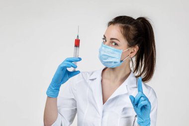 woman doctor in mask and rubber gloves holding syringe