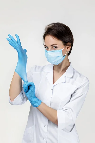 Woman doctor in white uniform wearing mask and rubber gloves — Stockfoto