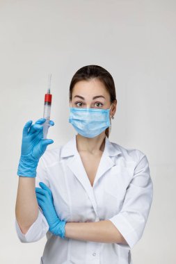 woman doctor in mask and rubber gloves holding syringe