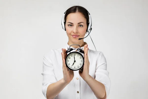 Woman consultant of call center in headphones holding alarm clock — Stok fotoğraf