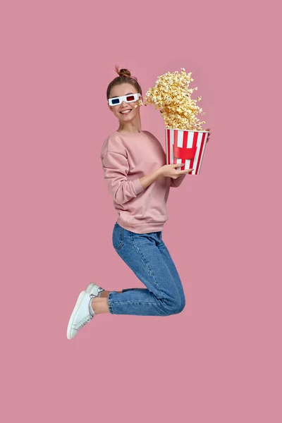 Женщина в красно-синих 3D очках держит ведро попкорна и прыгает — стоковое фото