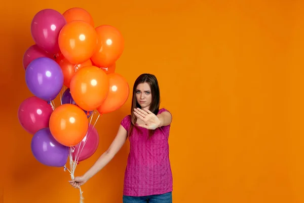 Жінка з яскравими різнокольоровими повітряними кульками, що показують стоп жест — стокове фото