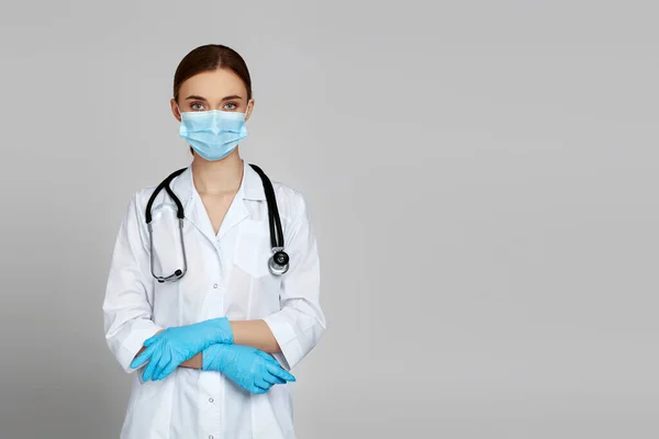 Портрет красивої жінки-лікаря в білому лабораторному пальто та стетоскоп ізольовані на сірому фоні — стокове фото