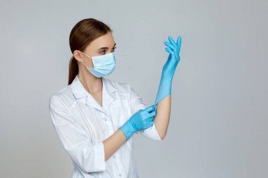 Beyaz üniformalı doktor maske ve lastik eldiven giyiyor.