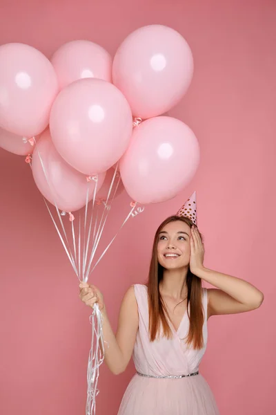 Kobieta w urodzinowym kapeluszu świętuje z pastelowymi różowymi balonami — Zdjęcie stockowe
