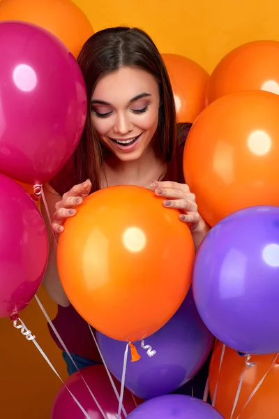 Усміхнена біла дівчина позує з яскравими кольоровими повітряними кульками — стокове фото