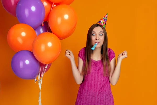 Mujer con brillantes globos de aire de colores soplando cuerno de fiesta — Foto de Stock