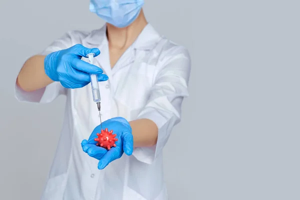 Woman doctor in mask and rubber gloves holding syringe and virus model — Stock Photo, Image