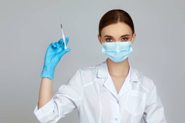 Gri arka planda şırınga tutan kadın doktor..