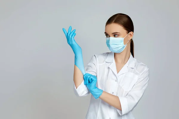 Läkare i vit uniform bär mask och gummihandskar — Stockfoto