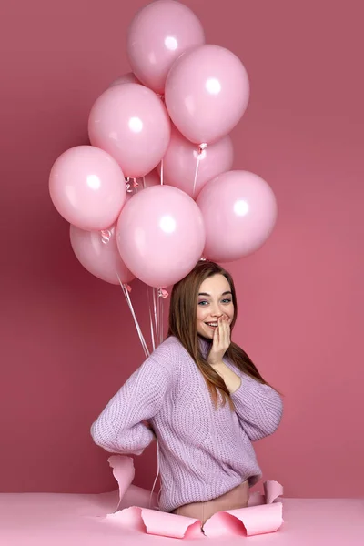 Mulher com balões de ar rosa pastel em pé em furo de papel rasgado — Fotografia de Stock