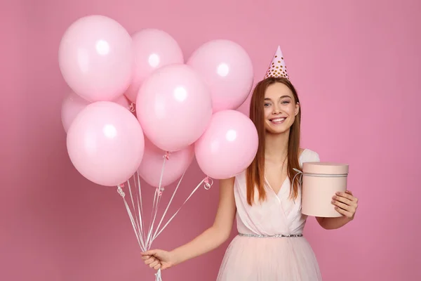 Femme en chapeau d'anniversaire célébrant avec des ballons à air rose pastel — Photo