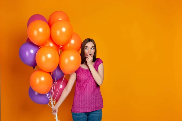 Pembe tişörtlü, parlak renkli hava balonları olan bir kadın. — Stok fotoğraf