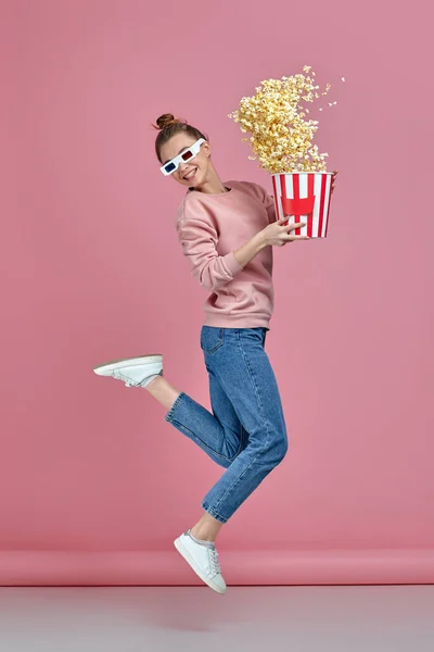 woman in red-blue 3d glasses holding popcorn bucket and jumping