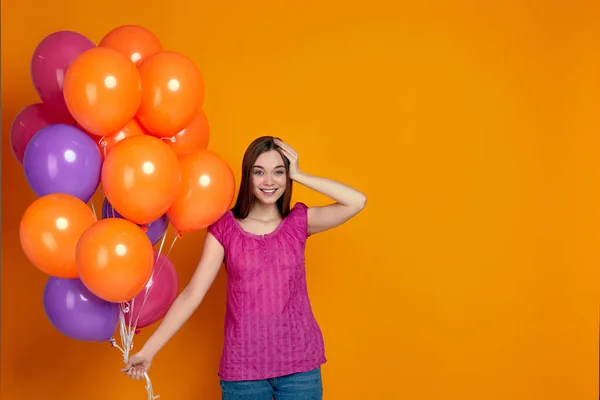 Mujer sorprendida posando con globos de aire de colores brillantes — Foto de Stock