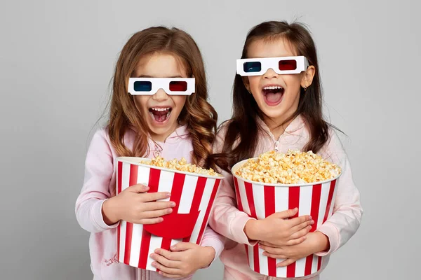 Deux petites filles dans des lunettes 3d rouge-bleu tenant des seaux de maïs soufflé — Photo
