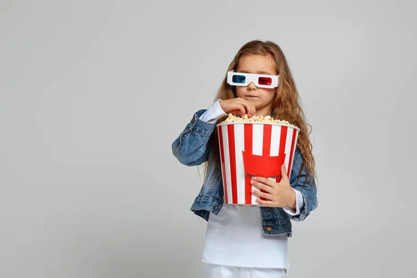 Enfant fille portant rouge-bleu 3d lunettes avoir du plaisir et tenant seau de maïs soufflé — Photo