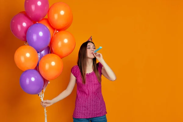 Vrouw met heldere kleurrijke lucht ballonnen blazen partij hoorn — Stockfoto