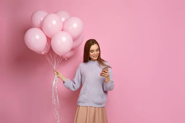 스마트 폰을 들고 있는 파스텔 핑크 풍선을 든 소녀 — 스톡 사진