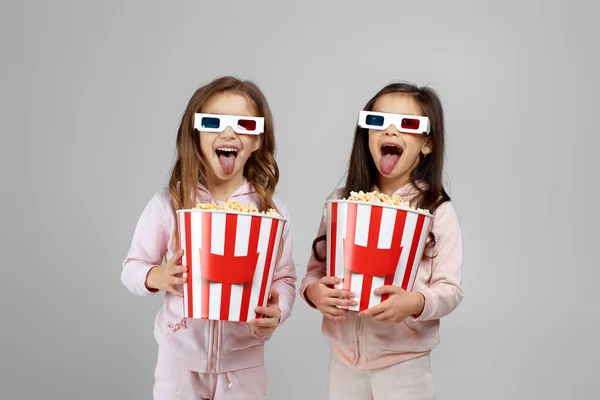 Дві маленькі дівчата в червоно-синіх 3d окулярах тримають попкорнні відра — стокове фото