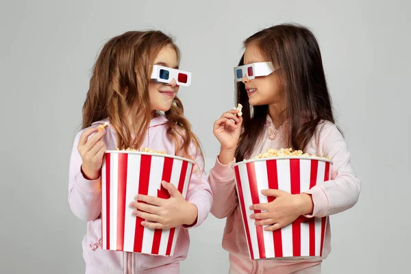 Two little girls wearing red-blue 3d glasses and eating popcorn — Stock Photo, Image