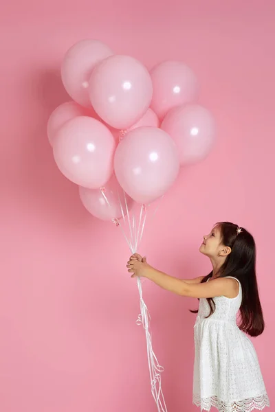 Gelukkig schattig klein kind meisje poseren met pastel roze lucht ballonnen — Stockfoto