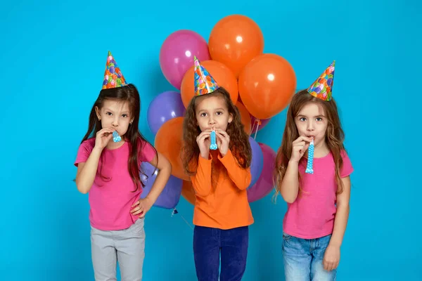 Niños en sombrero de cumpleaños con brillantes globos de aire de colores soplando cuerno de fiesta —  Fotos de Stock