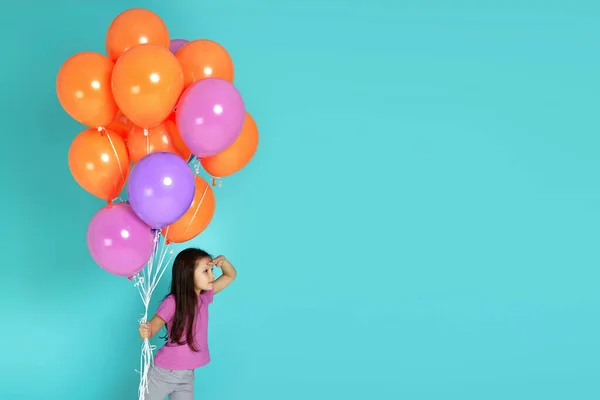 Bonito caucasiano menina criança com balões coloridos olhando para longe com a mão sobre a cabeça isolado no fundo azul. Conceito de pesquisa . — Fotografia de Stock