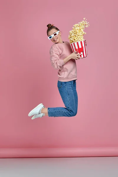 Женщина в красно-синих 3D очках держит ведро попкорна и прыгает — стоковое фото