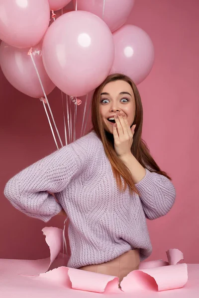 Mulher com balões de ar rosa pastel em pé em furo de papel rasgado — Fotografia de Stock