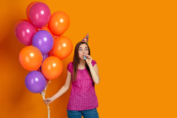 Mulher com balões de ar coloridos brilhantes soprando chifre de festa — Fotografia de Stock