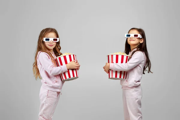 Deux petites filles dans des lunettes 3d rouge-bleu tenant des seaux de maïs soufflé — Photo