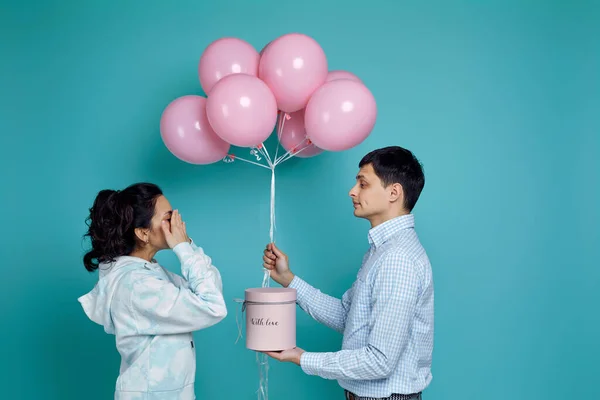 Muž představující růžové vzduchové balónky na přítelkyně na modrém pozadí — Stock fotografie