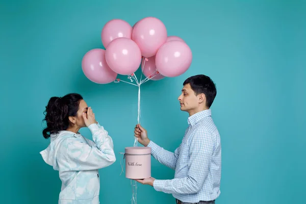 Hombre presentando globos de aire rosa a novia sobre fondo azul — Foto de Stock