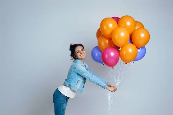 Flicka i denim poserar med ljusa färgglada luftballonger — Stockfoto