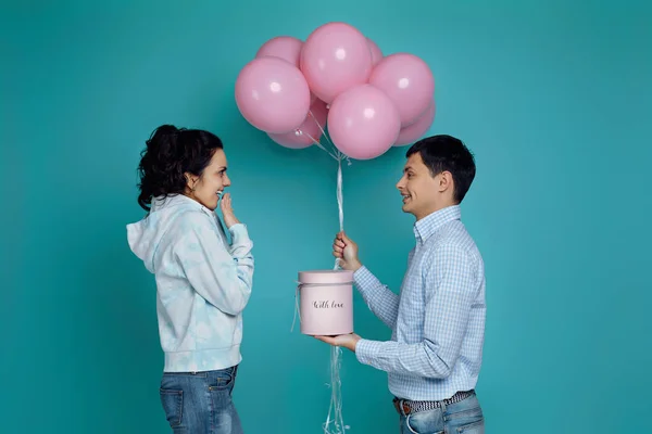 Homme présentant des ballons à air rose à petite amie sur fond bleu — Photo