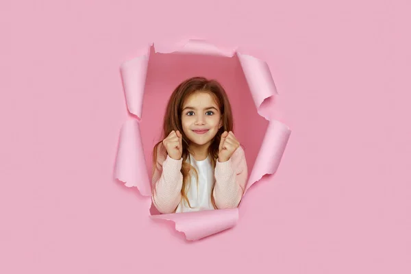 Портрет милої щасливої усміхненої білої маленької дівчинки, яка піднімає згорнуті кулаки — стокове фото