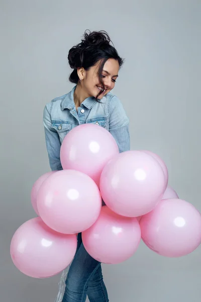 Menina em ganga segurando pastel balões de ar rosa — Fotografia de Stock
