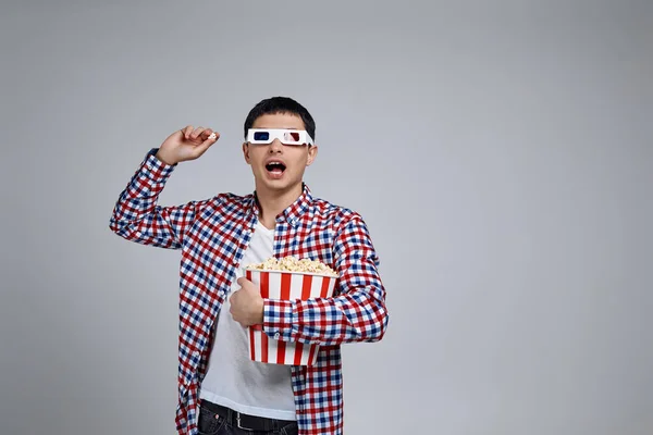 Hombre vistiendo gafas 3d rojo-azul y sosteniendo palomitas de maíz cubo — Foto de Stock