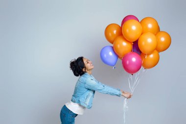Parlak renkli hava balonlarıyla poz veren kot giyen kız.