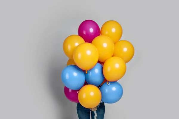 Frau versteckt sein Gesicht mit bunten Luftballons — Stockfoto