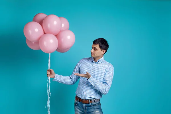 Homme en chemise pointant vers des ballons à air rose — Photo