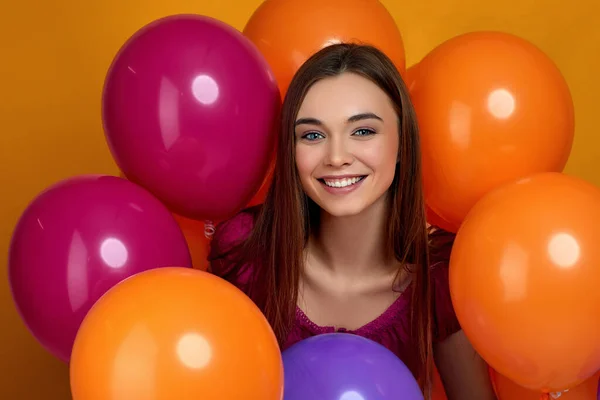 Усміхнена біла дівчина позує з яскравими кольоровими повітряними кульками — стокове фото