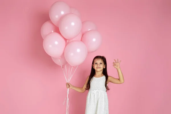 Sonriente niña adorable con globos de aire de color rosa pastel — Foto de Stock