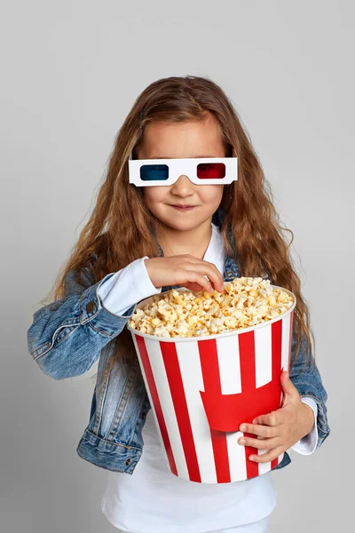 小女孩戴着红蓝色3D眼镜，玩的很开心，手里拿着爆米花桶 — 图库照片