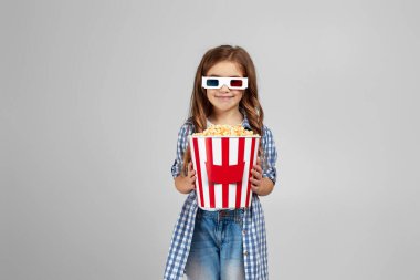 Kırmızı-mavi gözlük takan ve patlamış mısır yiyen çocuk.