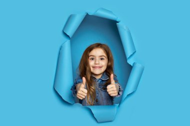 Beyaz tenli küçük kız başparmağını kaldırıyor.