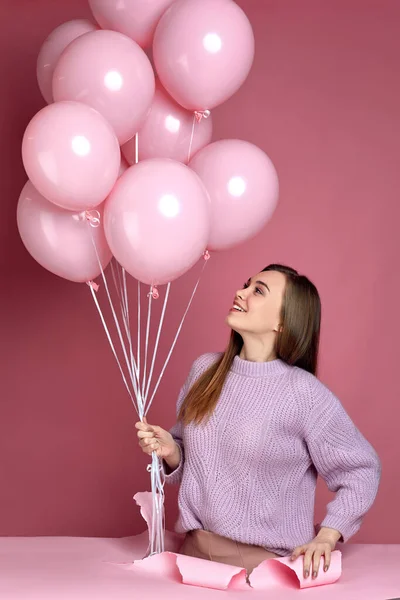 Kobieta z pastelowymi różowymi balonami powietrza stojąca w rozdartej papierowej dziurze — Zdjęcie stockowe