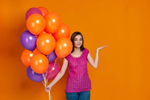 Mujer en camiseta rosa posando con globos de aire de colores brillantes — Foto de Stock